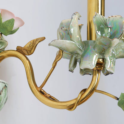 Detailed view of the brass arm’s polished finish and its connection to the ceramic floral arrangement.