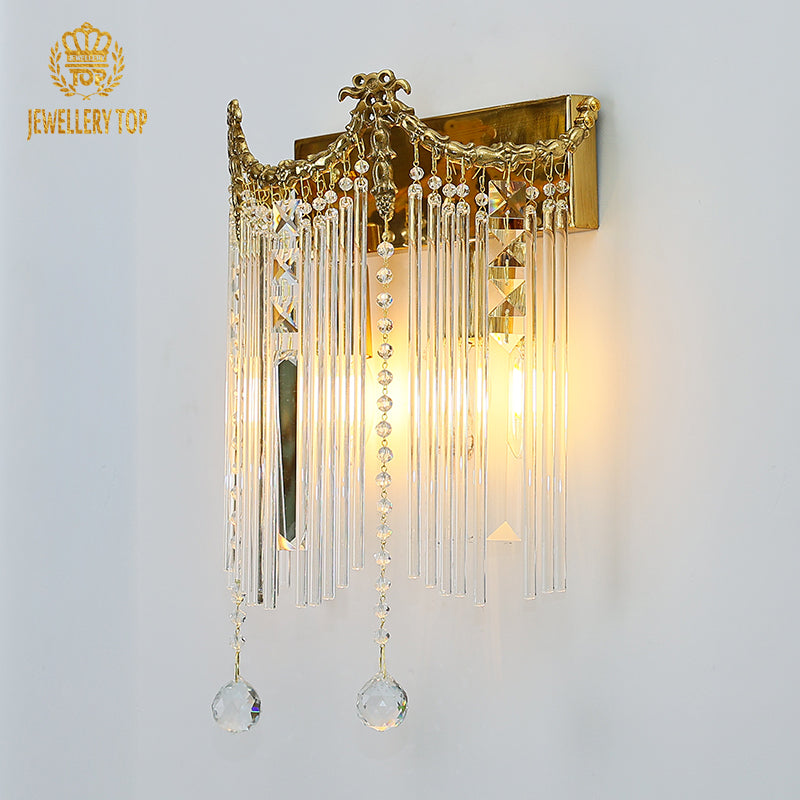 Close-up detail of the ornate Rococo-style brass scrollwork and the attached faceted crystal prisms on the sconce.