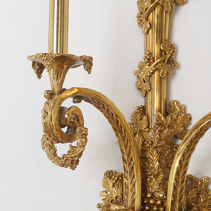 Detailed shot of the sconce’s ornate arm featuring intricate scrollwork and a candleholder.