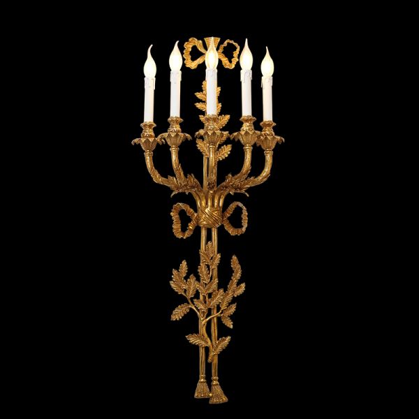 Extreme close-up macro detail of the sconce’s hand-chased acanthus leaf and ribbon brass decorations.