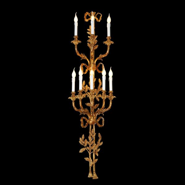 Front view of the grand Versailles Candelabra brass wall sconce with multiple candle lights and ornate scrollwork on black.