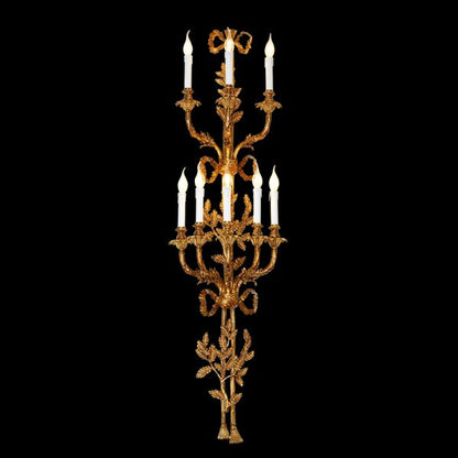 Front view of the grand Versailles Candelabra brass wall sconce with multiple candle lights and ornate scrollwork on black.