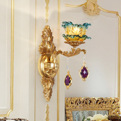 The retro brass wall lamp installed on a white and gold-accented wall, emitting a warm, colorful glow.