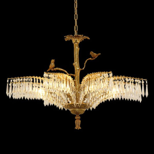 Close-up detail of antique brass chandelier with birds and layered crystal curtains.