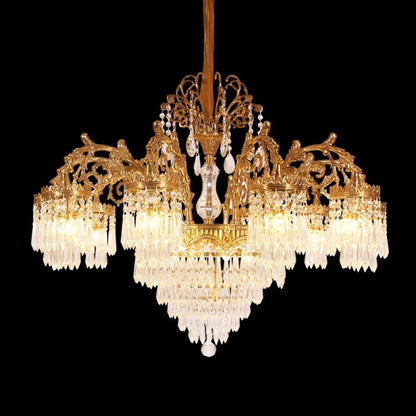 Side angle of a vintage European brass chandelier with scroll arms and crystal pendants.