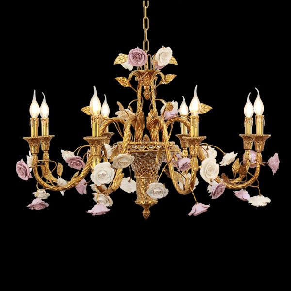 Close-up of vintage brass chandelier with white and lavender ceramic roses, isolated on black.