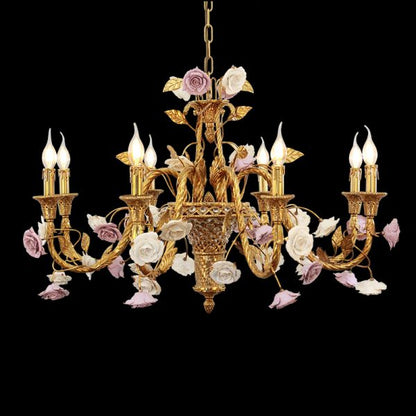 Close-up of vintage brass chandelier with white and lavender ceramic roses, isolated on black.