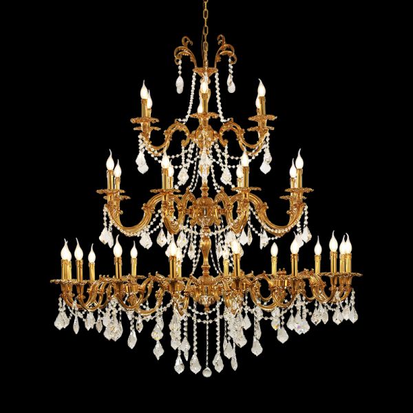 Close-up of a luxurious multi-tiered brass crystal chandelier with candle bulbs on black background.