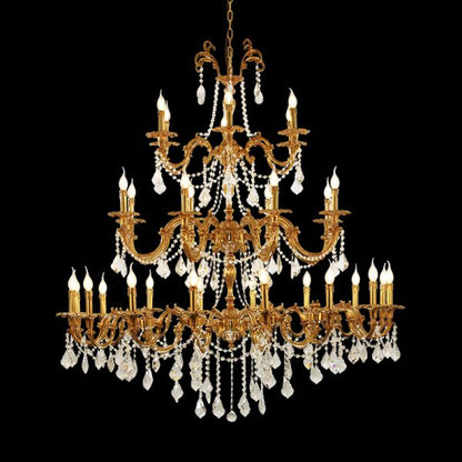 Close-up of a luxurious multi-tiered brass crystal chandelier with candle bulbs on black background.