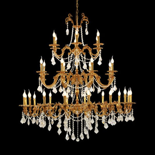 Close-up of a luxurious multi-tiered brass crystal chandelier with candle bulbs on black background.