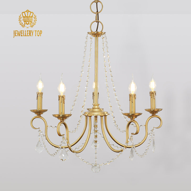 Close-up detail of the polished brass arms and crystal drop accents on a decorative chandelier.