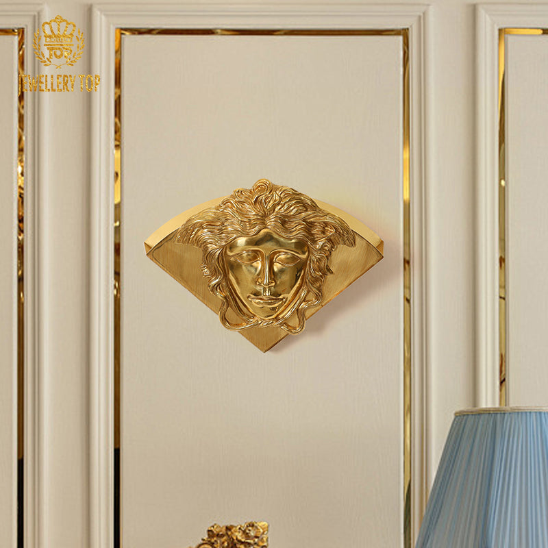 Installed French style brass wall lamp with a classical facial relief on a light wall with gold trim, brand JEWELLERY TOP.