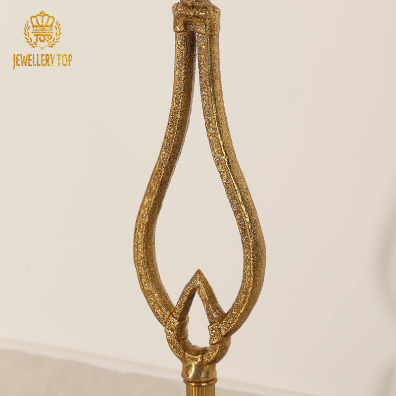 Close-up detail of the textured openwork lyre stem on the brass Chrysomallos table by Jewellery Top.