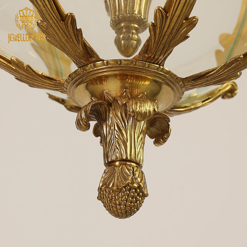 Macro detail of fruit cluster carvings and flared glass shades on a classical brass pendant light.