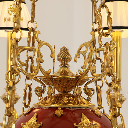 Close-up of intricate brass engraving and the red & gold central sphere of the chandelier.