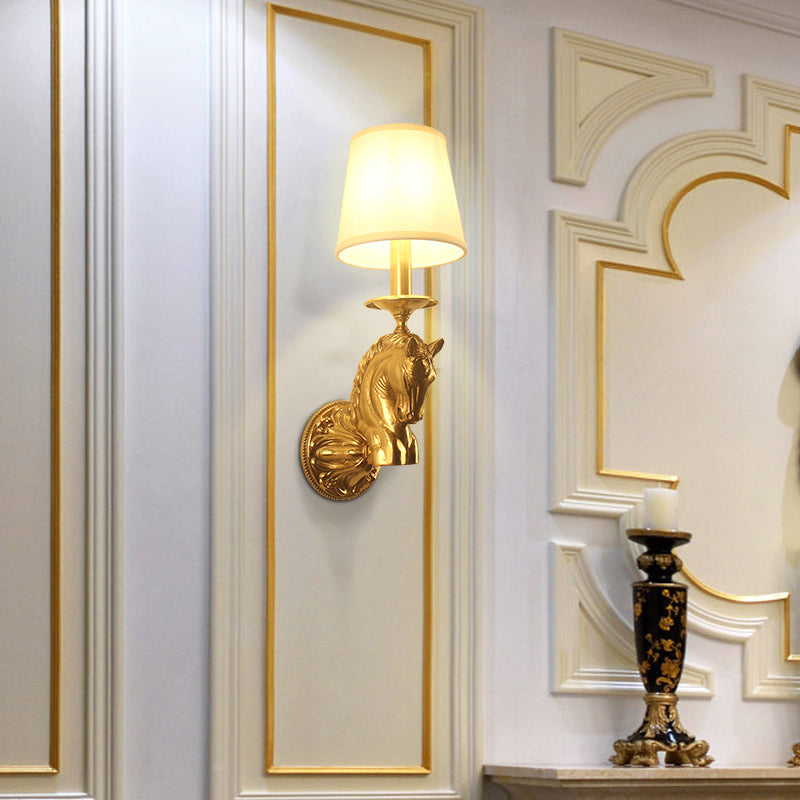 The decorative brass wall lamp installed on a white and gold-accented wall next to a black candlestick, showcasing its elegant ambiance.