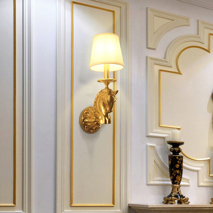 The decorative brass wall lamp installed on a white and gold-accented wall next to a black candlestick, showcasing its elegant ambiance.