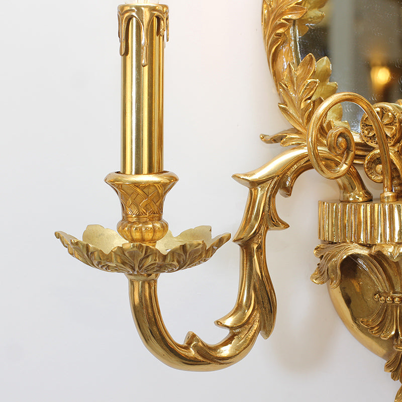 Macro detail shot of one curved arm, highlighting the intricate metal engraving and the candle-style bulb.