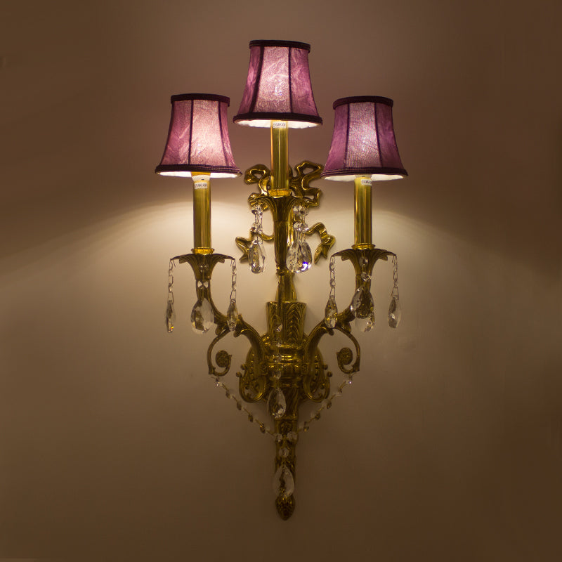 The Victorian-style brass wall lamp installed on an elegant dark blue wallpapered wall.