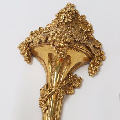 Extreme close-up macro detail of the hand-carved grape clusters and leaves on the brass arm.