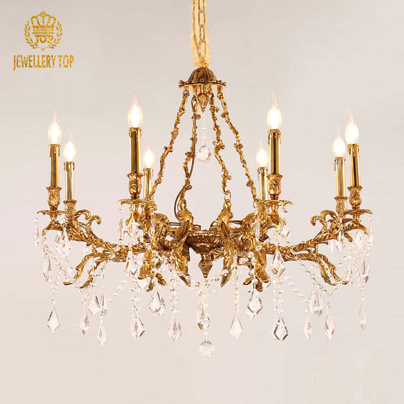 JEWELLERY TOP brand's ornate brass chandelier with lit bulbs and sparkling crystals on white.
