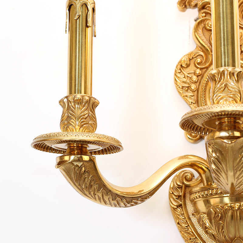 Extreme close-up macro detail of the sconce’s hand-chased floral and scroll patterns on the central brass column.