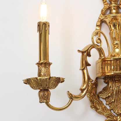 Side profile highlighting the curved arm, candle bulb, and exquisite metalwork of the sconce.