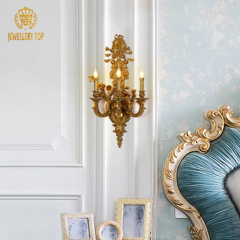 The vintage European brass wall lamp installed beside a blue upholstered headboard and gold-framed artwork.