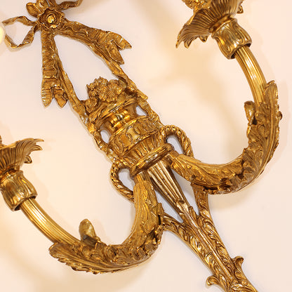 Extreme close-up macro shot of the intricately hand-carved floral and leaf patterns on the brass arm of the sconce.