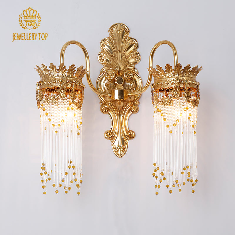 JEWELLERY TOP branded close-up of the ornate golden wall sconce with glowing bulbs and intricate metalwork.