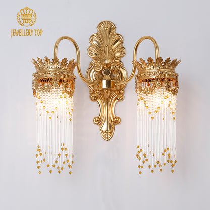JEWELLERY TOP branded close-up of the ornate golden wall sconce with glowing bulbs and intricate metalwork.