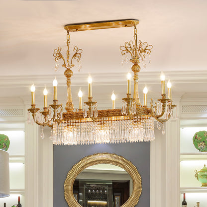 The crystal brass chandelier installed in a formal dining room with a round mirror and wainscoting.