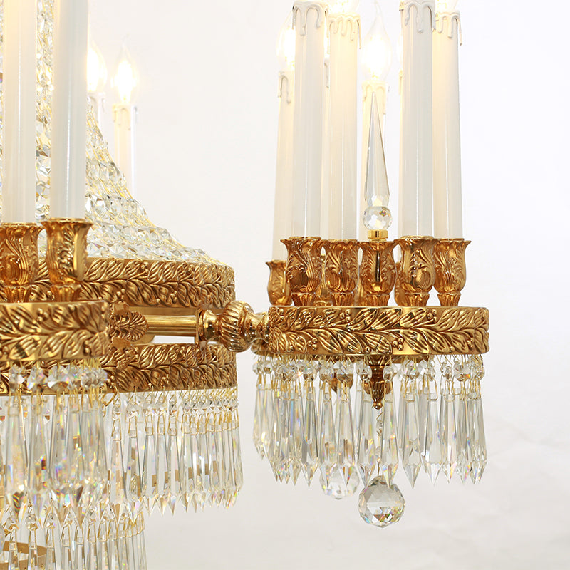 Close-up macro detail of ornate brass leaf engraving, a candle bulb, and crystal pendants.