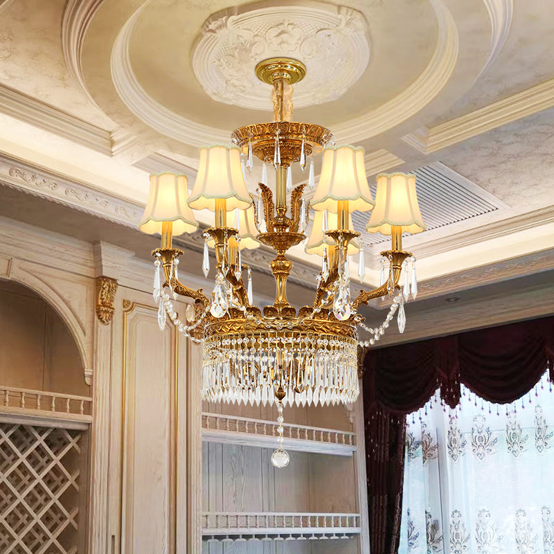 A European brass crystal chandelier installed under a decorative ceiling with patterned curtains.