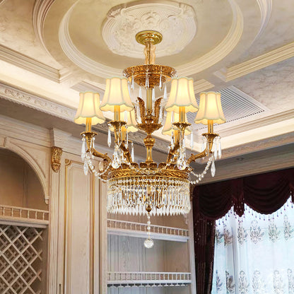 A European brass crystal chandelier installed under a decorative ceiling with patterned curtains.