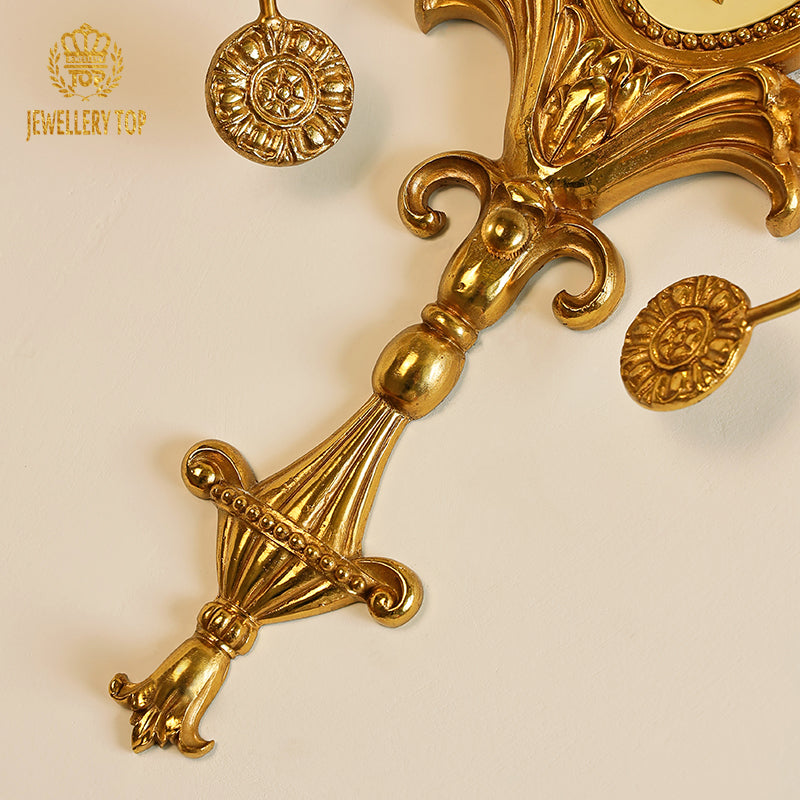 Extreme close-up of the golden Fleur-de-Lys (iris) finial and ornate scrollwork atop the bedroom wall lamp.