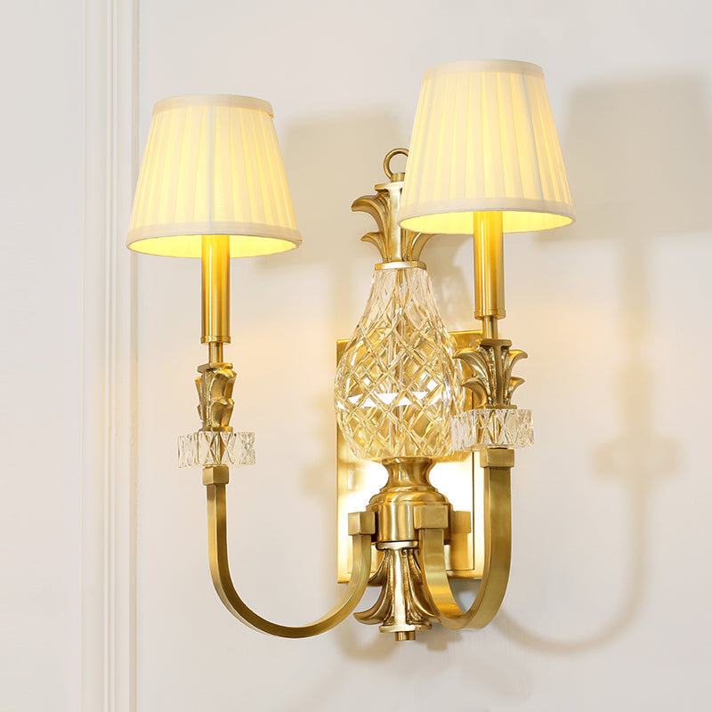 Close-up detail of the pleated white fabric lampshade and the ornate brass scrollwork arm.
