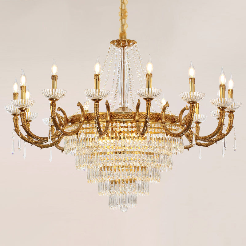 A lit, ornate crystal brass chandelier with multiple bulbs and layered pendants.