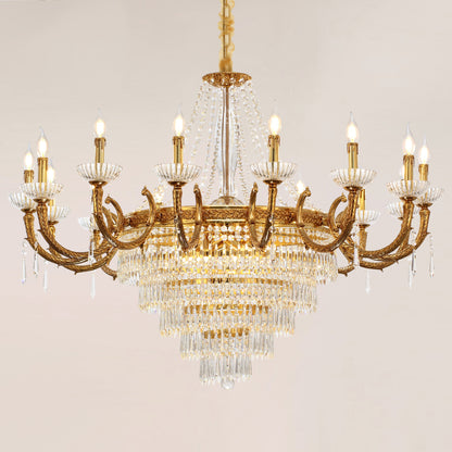 A lit, ornate crystal brass chandelier with multiple bulbs and layered pendants.