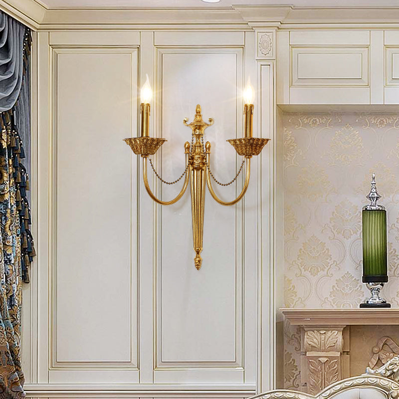 The vintage French brass wall lamp installed on white wainscoting beside a fireplace with green vase.
