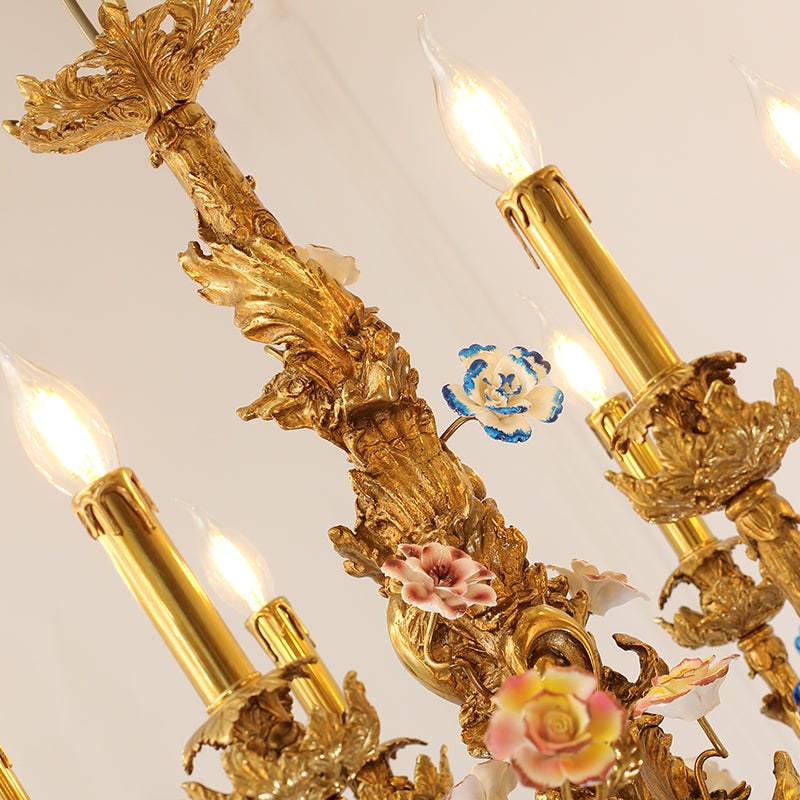Macro close-up of a pink and white ceramic rose and a blue flower on a brass chandelier arm.