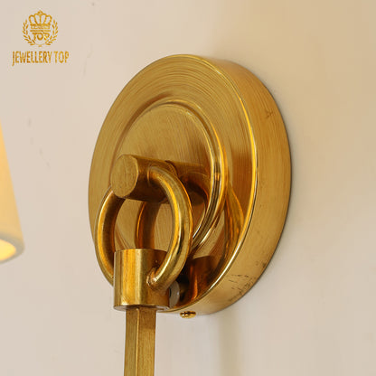 Focus on the connection between the brass arm and the pleated fabric shade of the luxury gold light.
