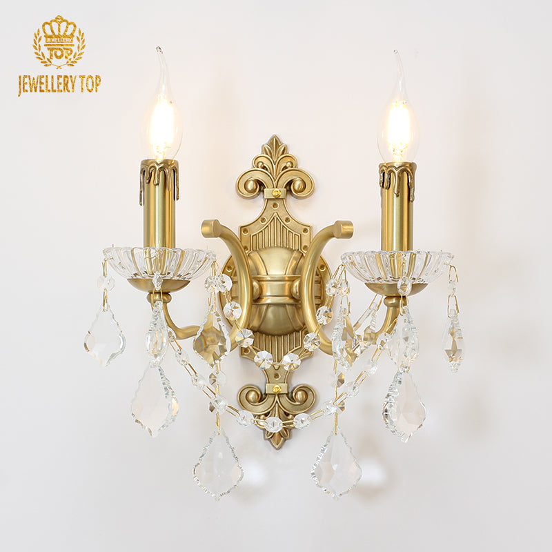 Front product view of the golden Harmonie Cristal brass wall sconce with two candles and crystal drops, JEWELLERY TOP logo.