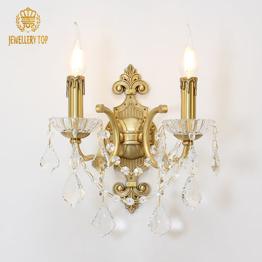 Front product view of the golden Harmonie Cristal brass wall sconce with two candles and crystal drops, JEWELLERY TOP logo.