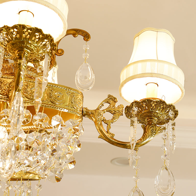 Close-up detail of ornate brass scrollwork, a fabric lampshade, and crystal pendants.