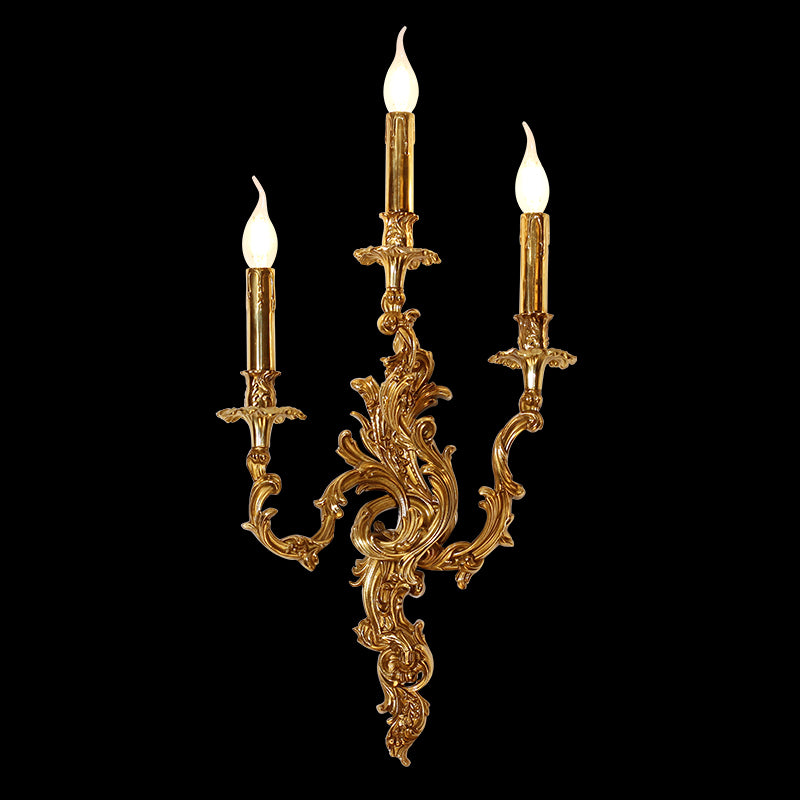 Isolated golden brass wall lamp with three candle-style arms against a black background, showcasing intricate Rococo scrollwork.
