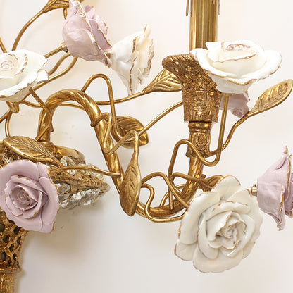 Extreme close-up of the hand-painted white and lilac ceramic roses with golden accents on the creative wall light.