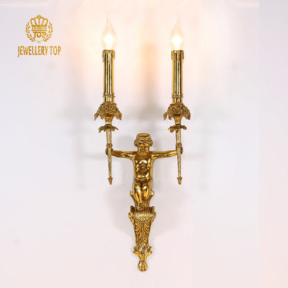 Close-up of the JEWELLERY TOP branded brass wall lamp, showcasing the angel figure and ornate arms on a white backdrop.