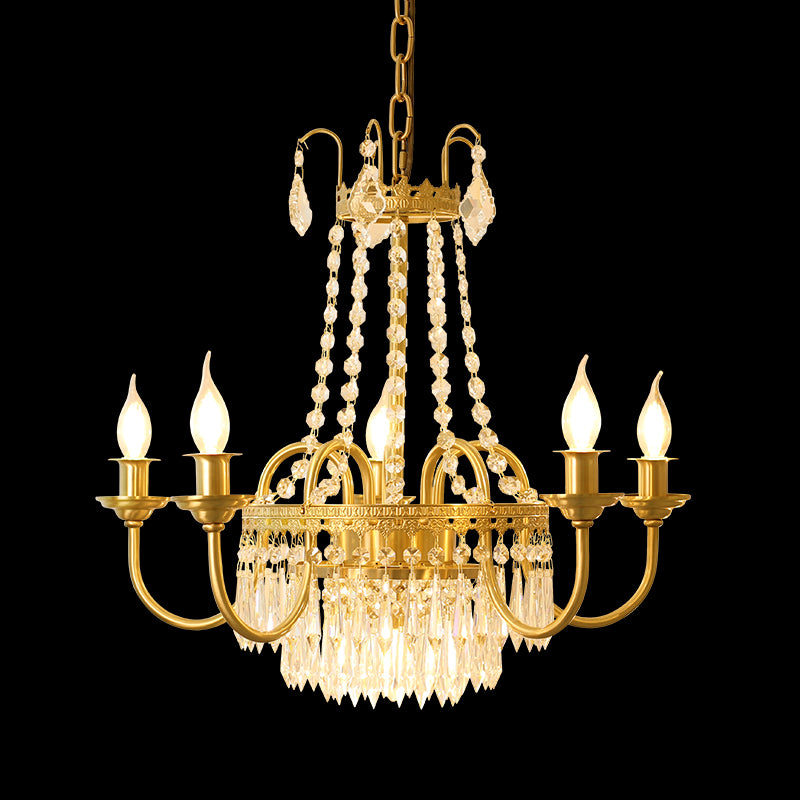 Close-up of a luxury brass chandelier with a central crystal cluster and six glowing bulbs.
