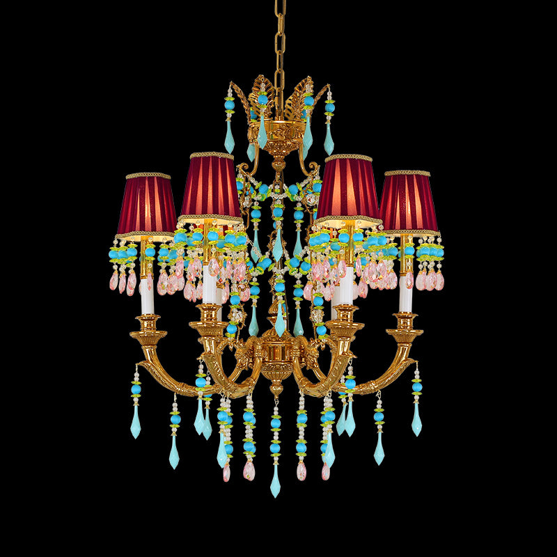 Close-up of a brass chandelier with red fabric shades and blue crystal decorations.